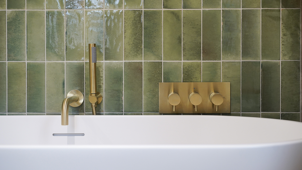 Freestanding bath brushed gold accents green tiles